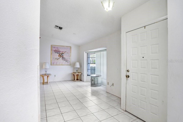 tiled foyer entrance with a textured ceiling and lofted ceiling