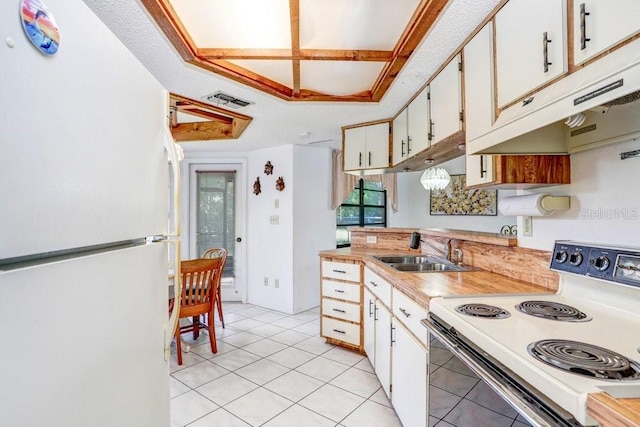 kitchen with sink, coffered ceiling, light tile patterned floors, white appliances, and white cabinets