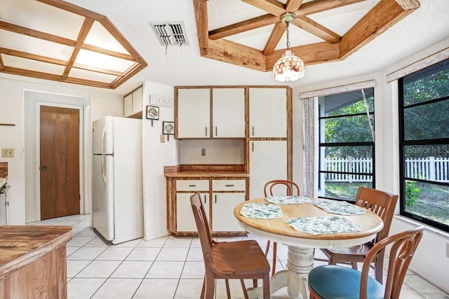 tiled dining area with an inviting chandelier, a textured ceiling, and a tray ceiling