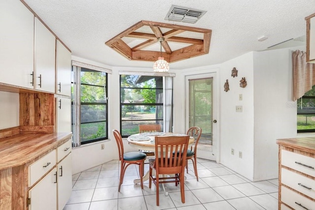 dining space featuring light tile patterned floors, a textured ceiling, a raised ceiling, and a notable chandelier