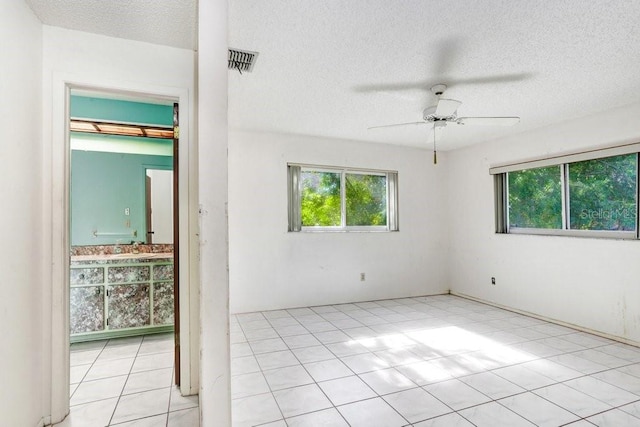 tiled empty room featuring ceiling fan and a textured ceiling