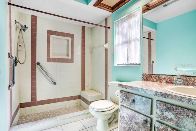 bathroom with tile patterned floors, toilet, a tile shower, and vanity