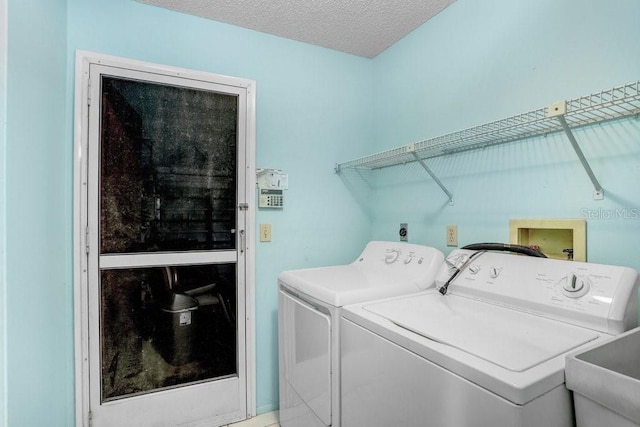 laundry room featuring a textured ceiling, separate washer and dryer, and sink