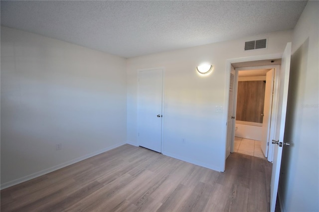 unfurnished bedroom with hardwood / wood-style floors, a textured ceiling, and a closet