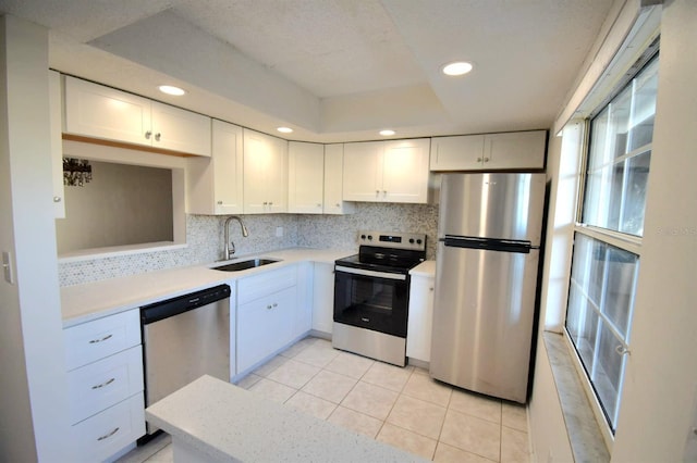 kitchen featuring white cabinets, appliances with stainless steel finishes, decorative backsplash, and sink