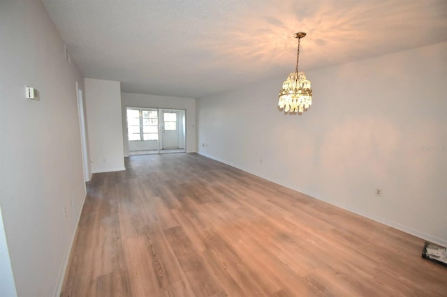 spare room with hardwood / wood-style floors, a textured ceiling, and an inviting chandelier