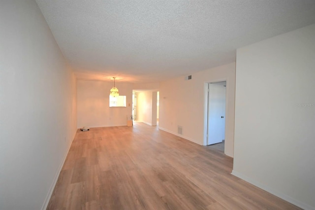 unfurnished room featuring a textured ceiling and light hardwood / wood-style floors