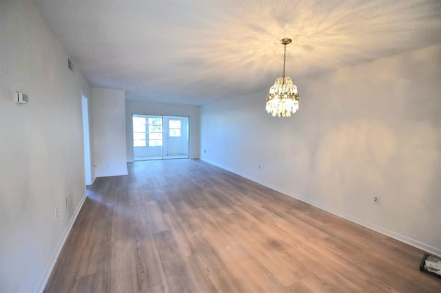 empty room featuring a chandelier and hardwood / wood-style floors