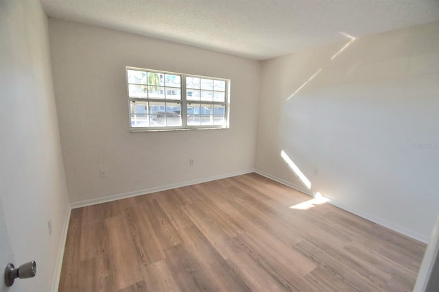 spare room featuring a textured ceiling and light wood-type flooring