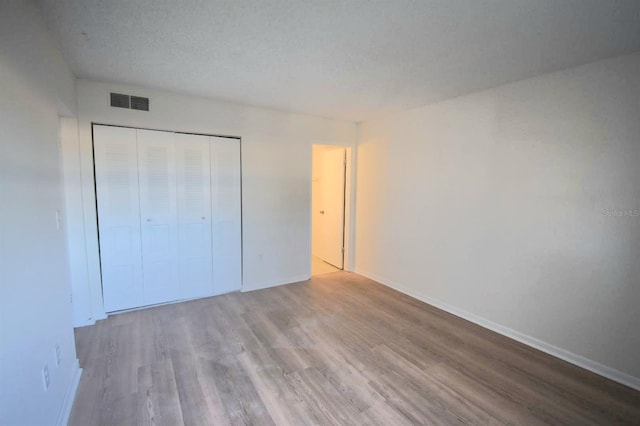 unfurnished bedroom featuring a closet, a textured ceiling, and hardwood / wood-style flooring