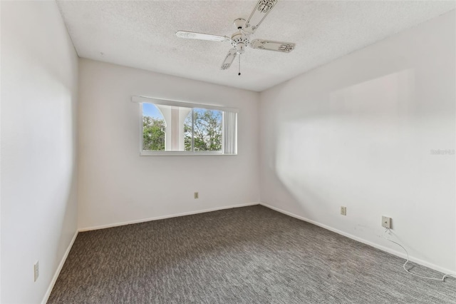 empty room featuring ceiling fan, dark carpet, and a textured ceiling