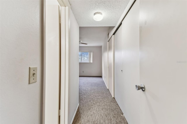 hallway featuring carpet flooring and a textured ceiling