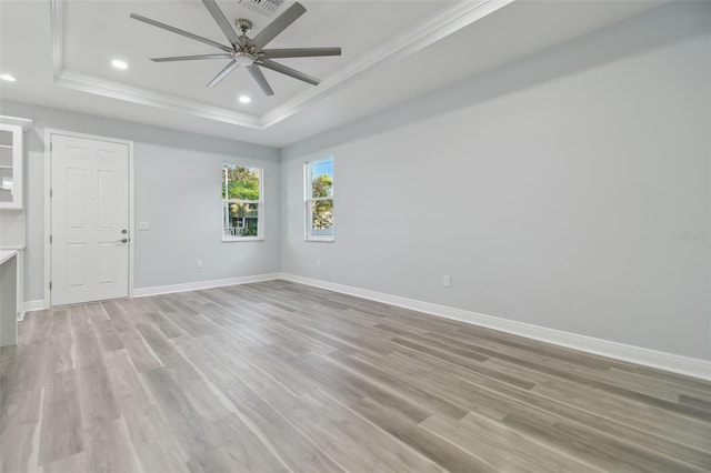 spare room featuring light hardwood / wood-style floors, a raised ceiling, ceiling fan, and crown molding