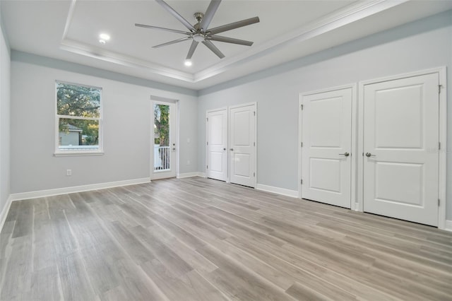 unfurnished bedroom featuring two closets, a raised ceiling, ceiling fan, access to exterior, and light hardwood / wood-style floors