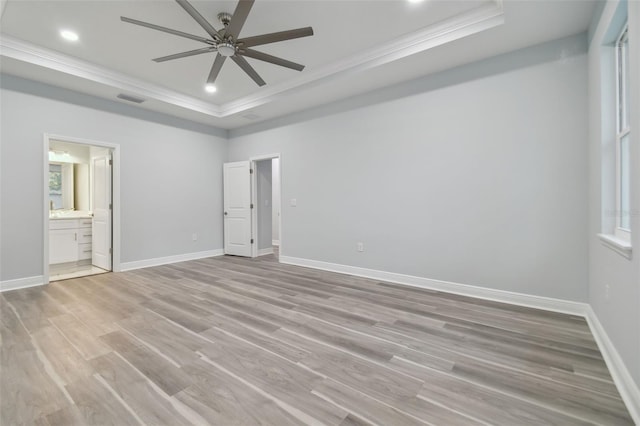 unfurnished bedroom with light wood-type flooring, ensuite bathroom, ornamental molding, a tray ceiling, and ceiling fan