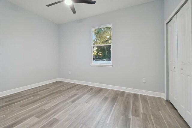 unfurnished bedroom with ceiling fan, light wood-type flooring, and a closet