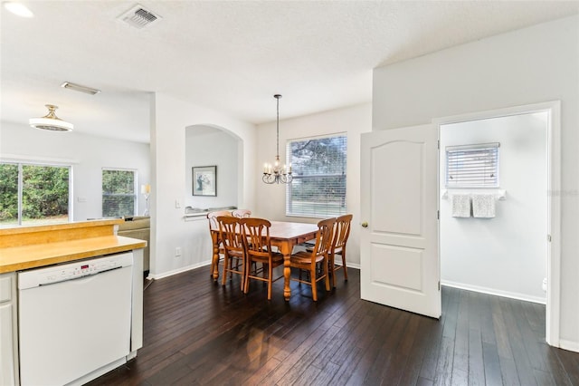 dining area with dark hardwood / wood-style floors, a textured ceiling, and an inviting chandelier