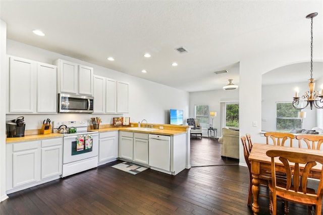 kitchen with pendant lighting, white appliances, white cabinets, sink, and kitchen peninsula