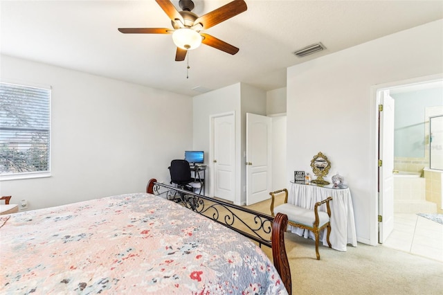 bedroom featuring light colored carpet, ensuite bath, and ceiling fan