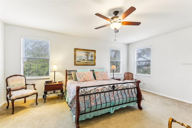 bedroom with ceiling fan, light carpet, and multiple windows