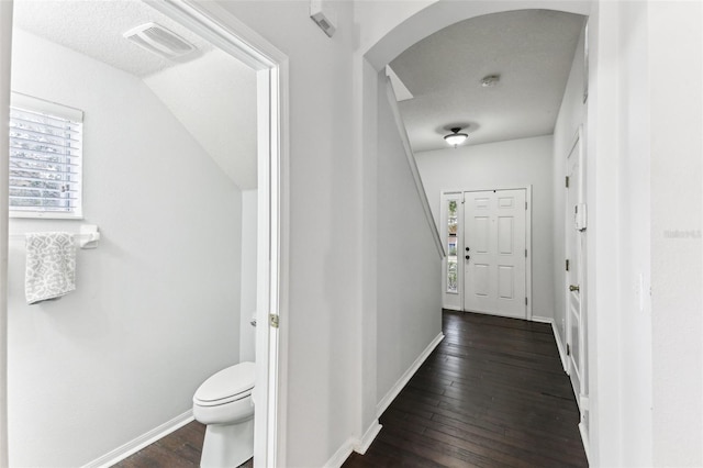 corridor featuring a textured ceiling, dark hardwood / wood-style floors, and vaulted ceiling