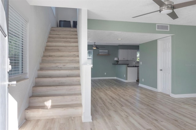 staircase featuring ceiling fan and hardwood / wood-style floors