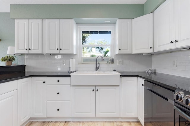 kitchen featuring tasteful backsplash, white cabinetry, and sink