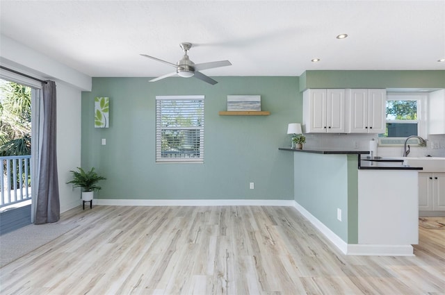 kitchen featuring white cabinets, ceiling fan, sink, and backsplash