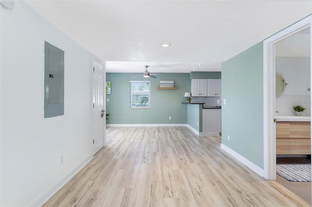 unfurnished living room featuring electric panel, ceiling fan, and light hardwood / wood-style floors