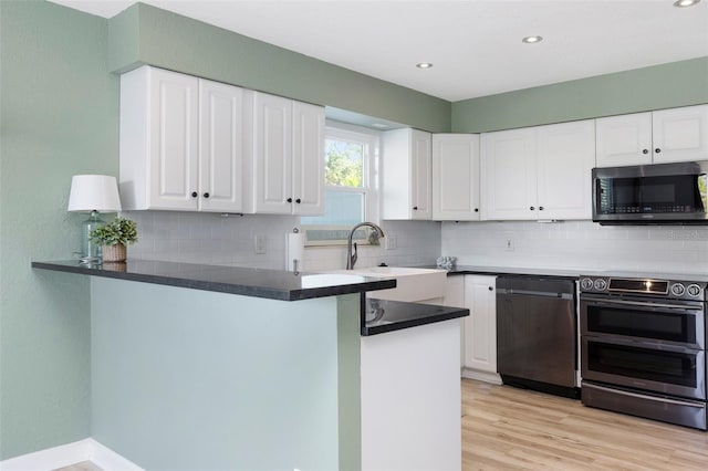 kitchen featuring kitchen peninsula, light wood-type flooring, stainless steel appliances, sink, and white cabinetry