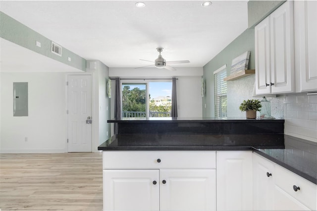 kitchen with decorative backsplash, light hardwood / wood-style floors, ceiling fan, white cabinets, and electric panel