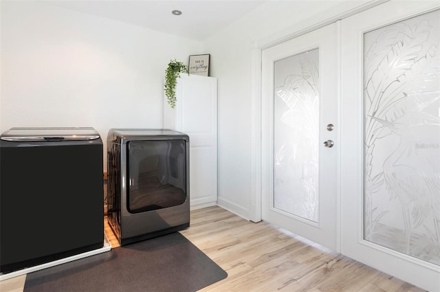 clothes washing area with light wood-type flooring and washer and clothes dryer