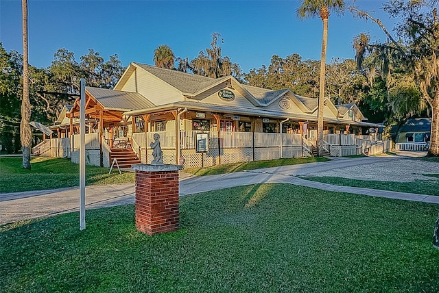 view of front facade featuring driveway, a front lawn, and fence