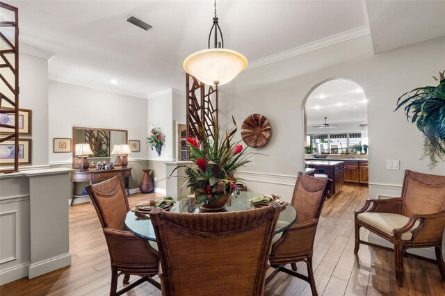 dining room with light hardwood / wood-style floors, ornamental molding, and ceiling fan