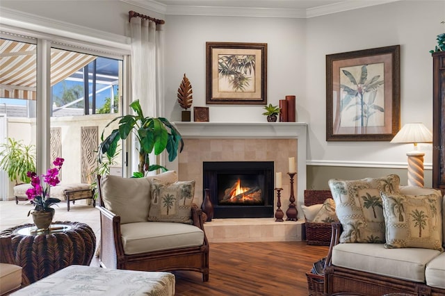 living area with hardwood / wood-style flooring, ornamental molding, and a fireplace