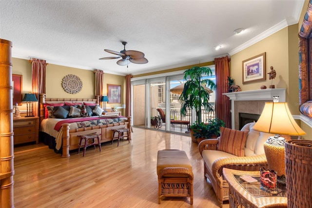 bedroom featuring ceiling fan, access to outside, a fireplace, a textured ceiling, and crown molding