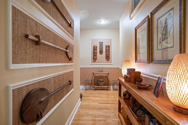 hall featuring a textured ceiling and light hardwood / wood-style flooring