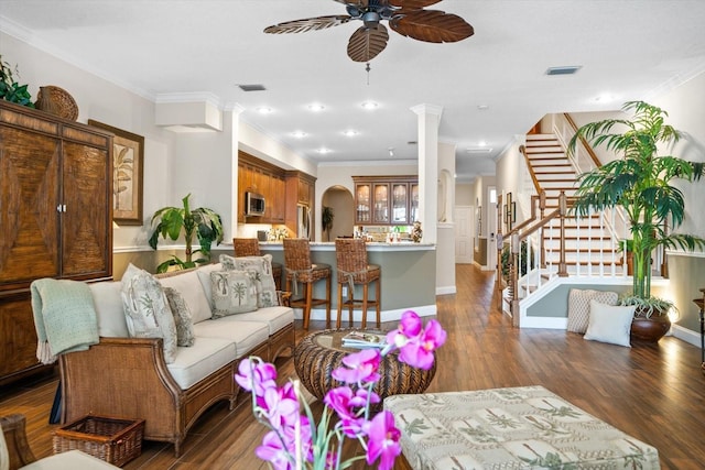 living room with dark wood-type flooring, ceiling fan, and crown molding