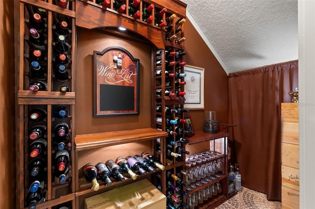 wine room with a textured ceiling, crown molding, and lofted ceiling