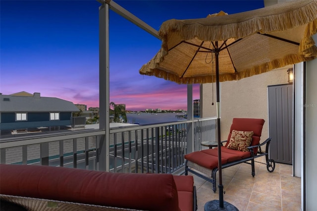 balcony at dusk featuring a water view