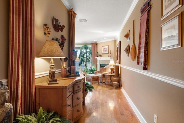 corridor with light wood-type flooring and crown molding