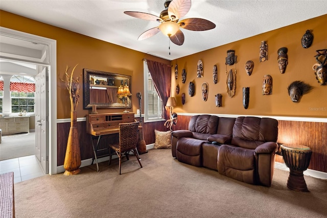 carpeted office with ceiling fan, wood walls, and a textured ceiling