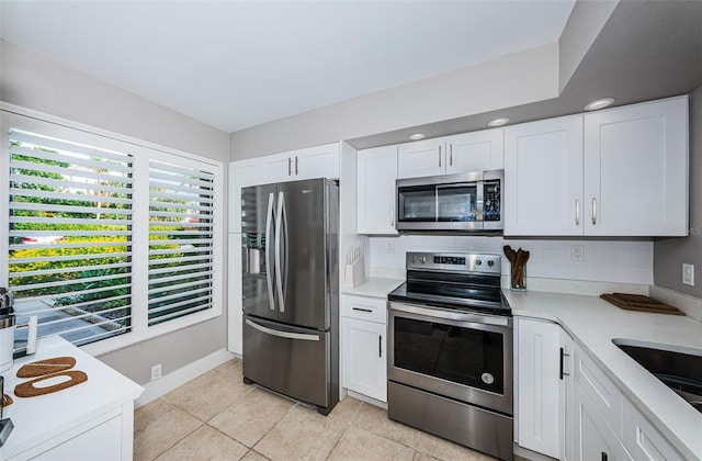 kitchen with white cabinets, light tile patterned floors, sink, and appliances with stainless steel finishes