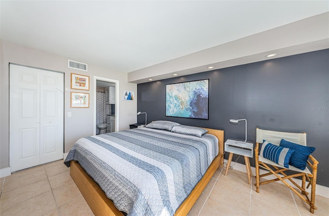 bedroom featuring ensuite bathroom, light tile patterned flooring, and a closet