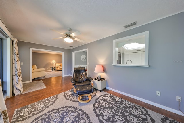 living area featuring wood-type flooring, a textured ceiling, and ceiling fan