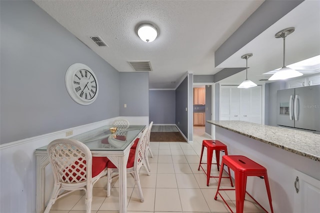 dining space featuring light tile patterned flooring and a textured ceiling