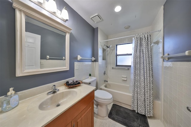 full bathroom with tile patterned floors, shower / bath combination with curtain, toilet, vanity, and tile walls