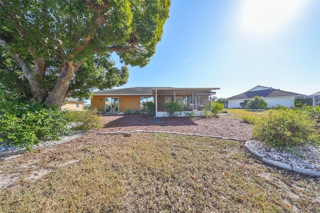 rear view of property with a lawn and a sunroom