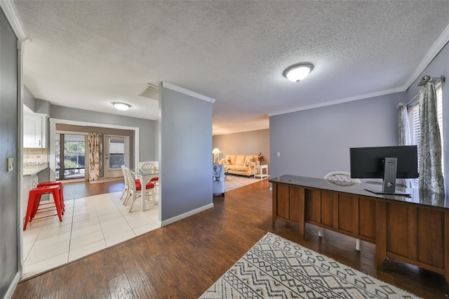 home office with a textured ceiling, light wood-type flooring, and crown molding