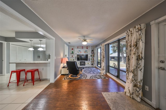 living room with ceiling fan, light hardwood / wood-style floors, and a textured ceiling